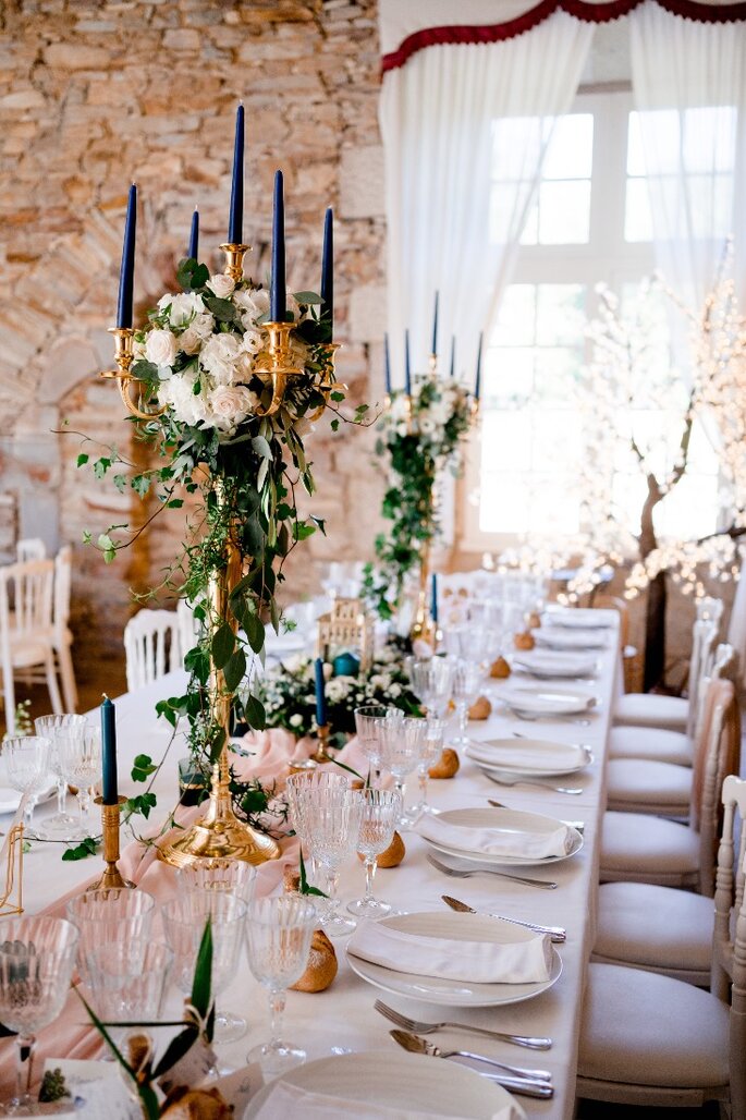 Table de mariage décorée avec des chaises blanches et de grands chandeliers dorés