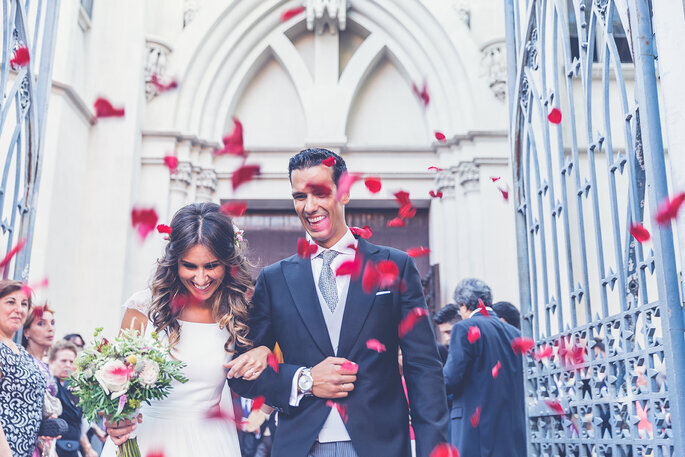 novios saliendo de la ceremonia mientras les avientan petalos de rosa