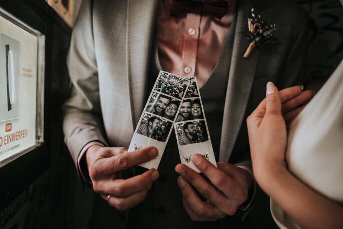 Der Bräutigam hält die Fotos as der Fotobox in der Hand, organisiert von Freakin' Fine Weddings.