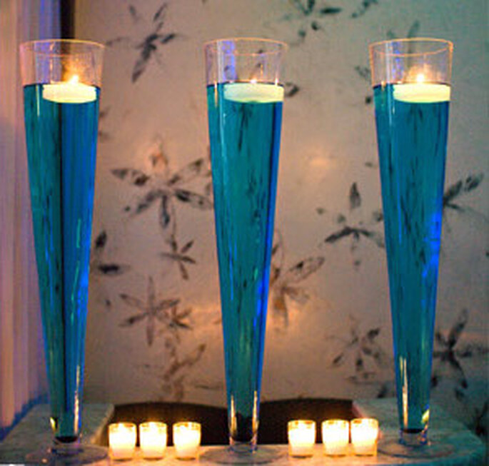 Floreros decorados con liquido azul y velas flotantes blancas