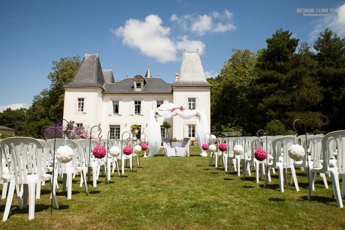 Des rangs de chaises blanches disposées devant le Château du Domaine de la Pinelais 