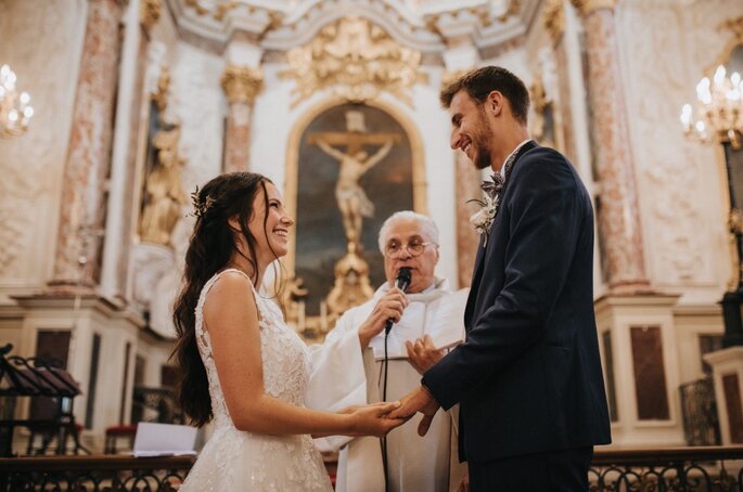 Prière universelle de mariage lue par le prêtre dans une église, deux mariés se font face 