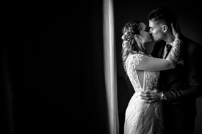 un couple de mariés s'embrassent en noir et blanc 