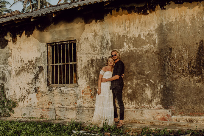 Das Brautpaar steht vor einem alten Gebäude und hält sich in den Armen.