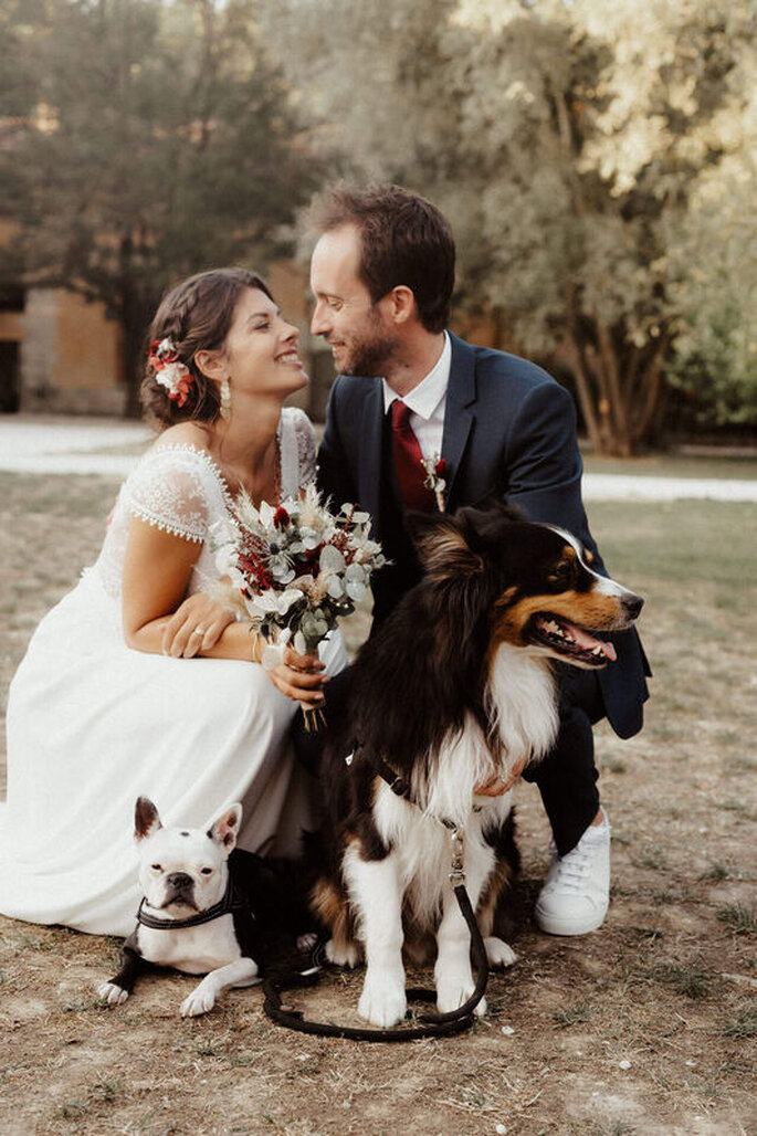 Couple de mariés agenouillés dans un parc en compagnie de leurs chiens