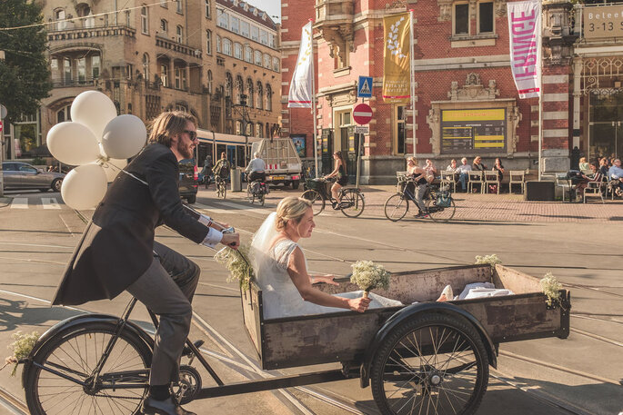 Noivo carregando a noiva em bicicleta com carrinho