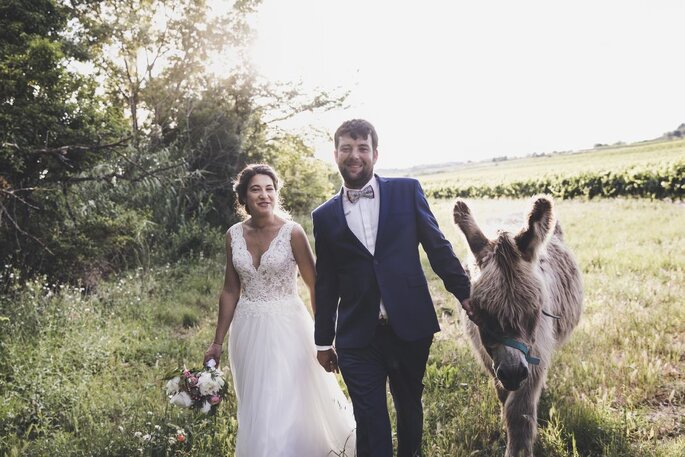 Ma Petite Cérémonie - Deux mariés se tenant par la main et promenant un poney dans un champ 