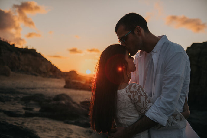 Casal numa praia a beijar-se ao por-do-sol