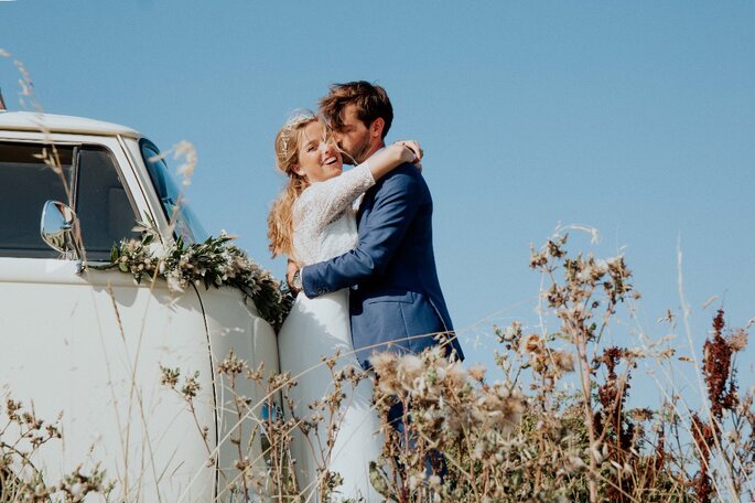 Deux mariés s'embrassent devant un van 