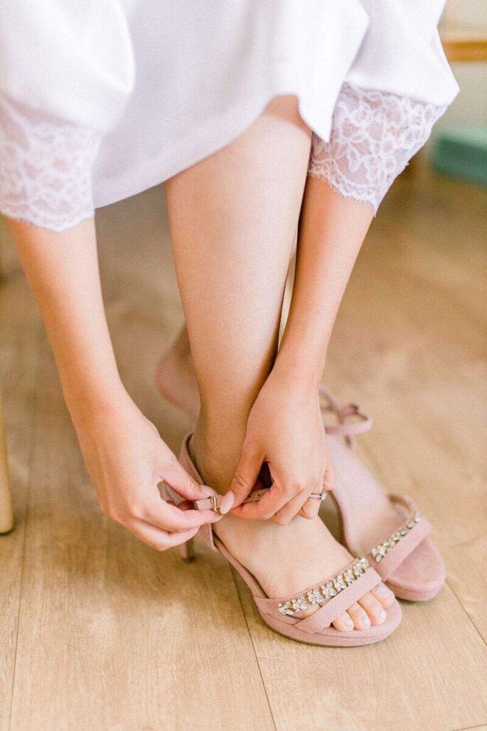 Les préparatifs d'une mariée qui attache ses chaussures couleur nude