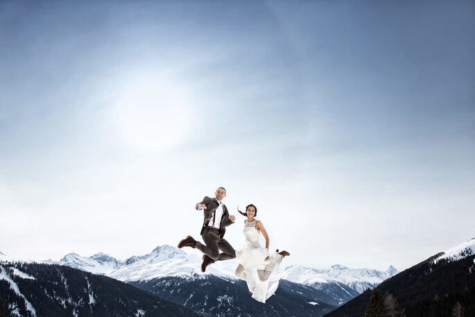 Brautpaar springt vor Bergkulisse, fotografiert von Thomas Hinder Fotografie