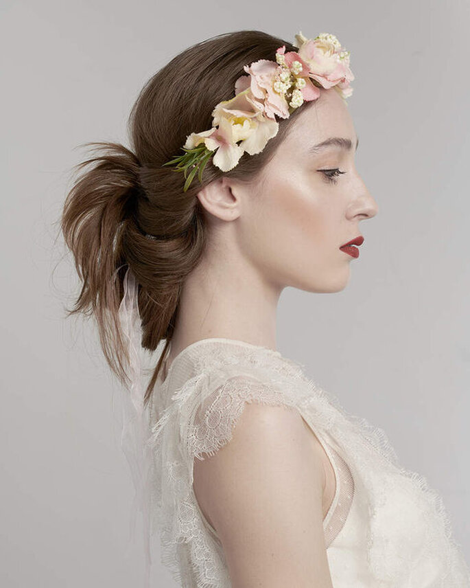 Une coiffure de mariage tendance - La mariée porte une couronne de fleurs qui descend sur son front et un chignon original 