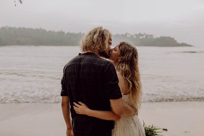 Das Brautpaar küsst sich am Strand.