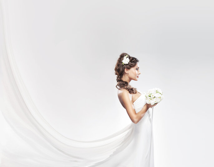 Novia con vestido y bouquet blanco. Foto vía Shutterstock