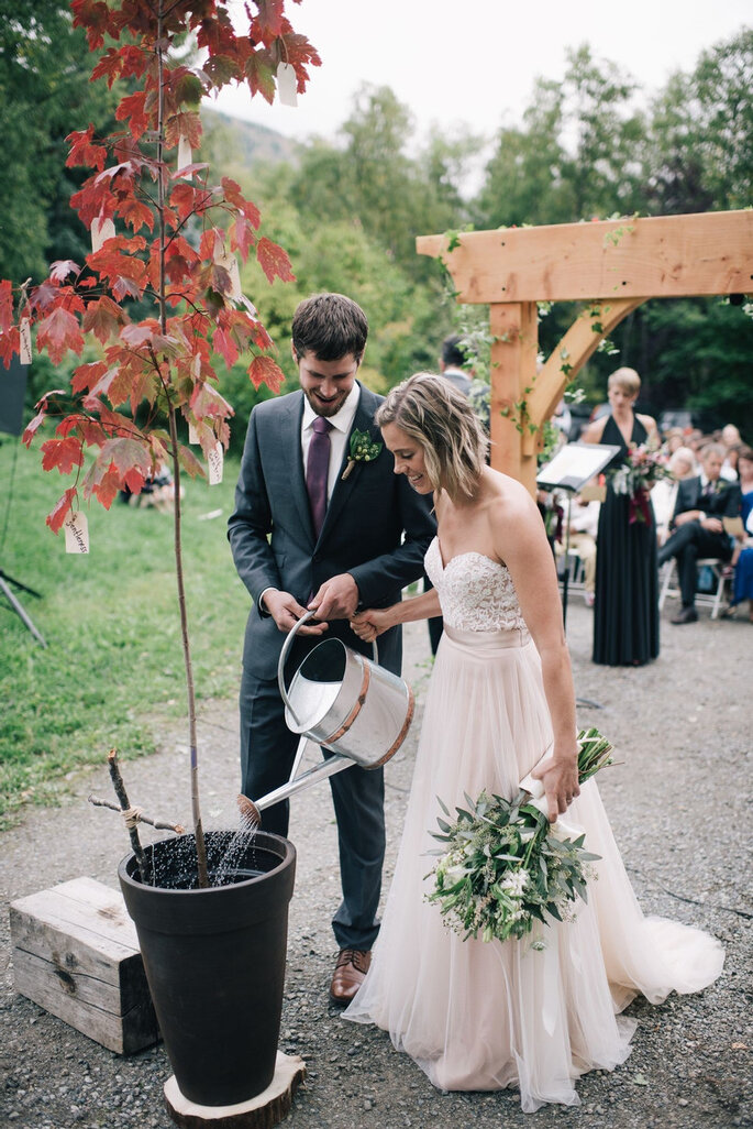 Pareja de novios plantando un árbol el día de su boda de temática ecológica