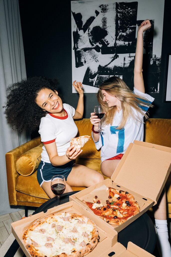 Domowa impreza - uśmiechnięte dziewczyny jedzące pizzę