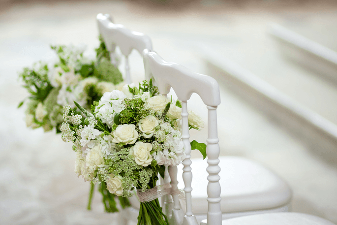 Chaises ornées de bouquets de fleurs blanches pour une cérémonie laïque en extérieur