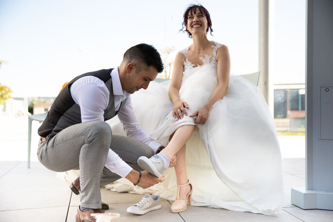Le futur marié enlève les baskets de sa femme pour lui faire passer des chaussures à talons beige 