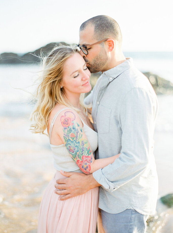 noivos a beijarem-se na praia noiva com tatuagem no braço