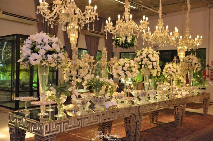 Mesa de doces luxuosa com lustres de cristais, flores brancas e espelhos