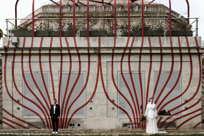 Un couple de mariés pose devant un mur à la peinture originale et artistique