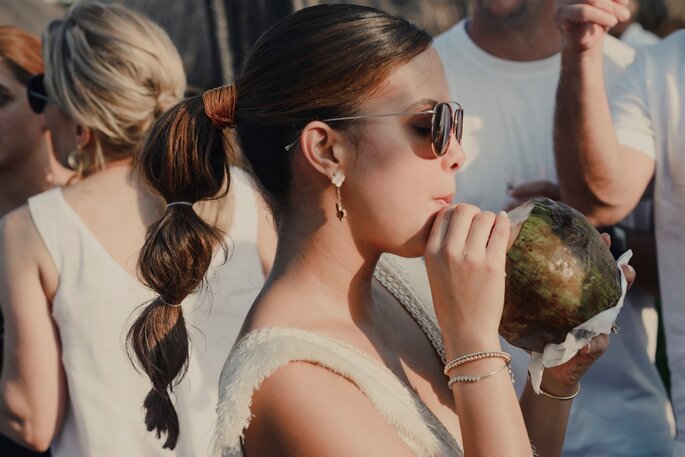 Novia en la playa bebiendo un coctel de coco