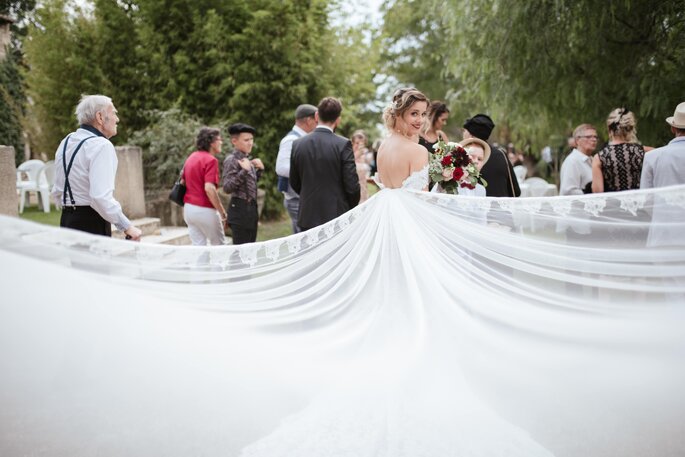  Souffles des Fées - une mariée montrant sa longue traîne avec tous les invités du mariage pour spectateurs