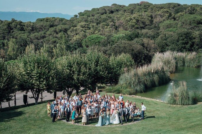 Les mariés et leurs invités posent dans un parc arboré, à côté d'un joli plan d'eau