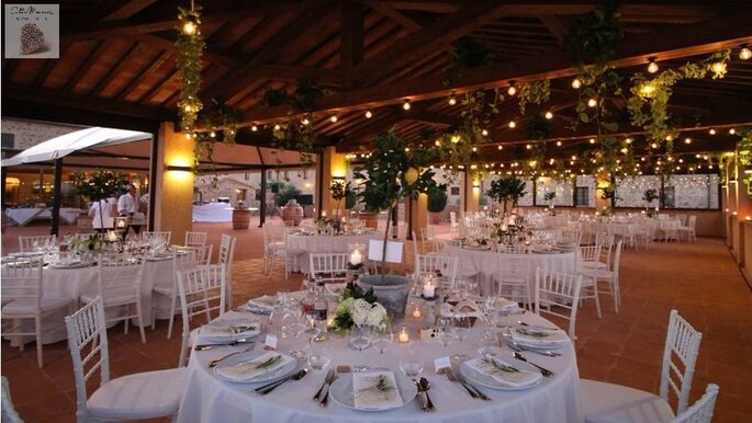 Dîner de mariage organisé en extérieur sous un préau, joliment illuminé à la tombée de la nuit