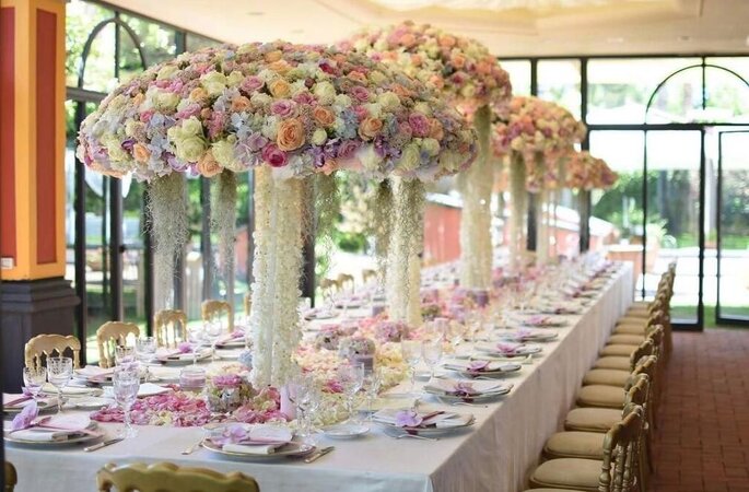 tavolata con tanti vasi alti e decorazioni floreali a ombrello