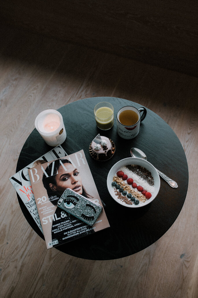 Ein Café-Tisch mit verschiedenen Zeitschriften, Getränken und eine Frühstücksbowl.