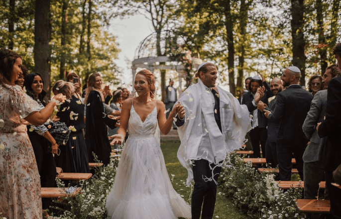 Les mariés sous les ovations de leurs invités à la fin de leur cérémonie en extérieur