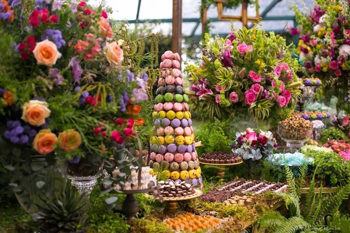 Decoração de casamento tropical com torre de macarrons, flores e tons coloridos e muita vegetação.
