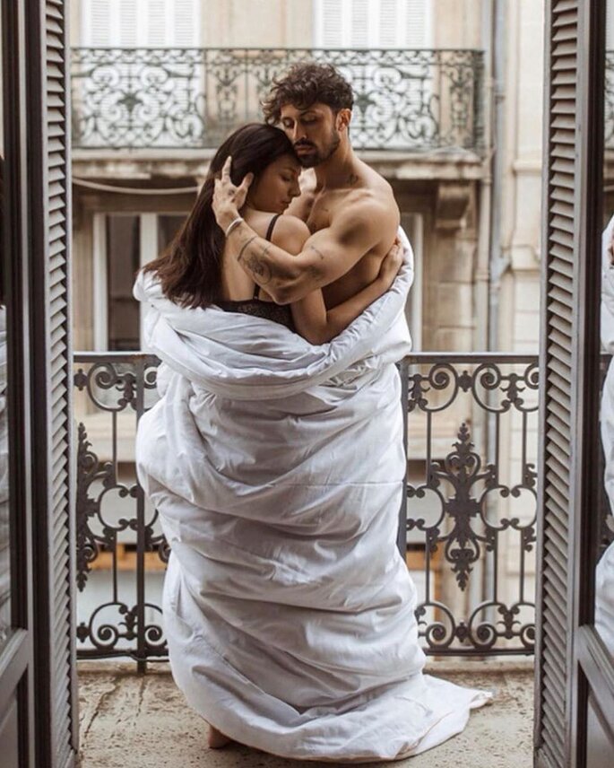 Paar auf Balkon sich umarmend mit Decke