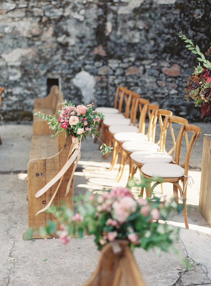 cadeiras de madeira com estofado claro e arranjo de flores rosa em cerimônia ao ar livre