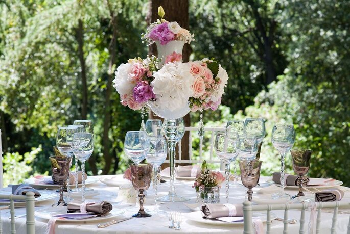 Une table dressée dans un jardin avec une superbe composition de fleurs pour un mariage 