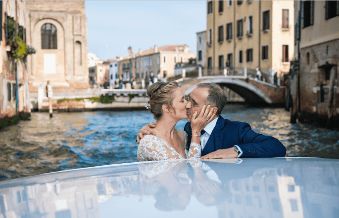 les mariés s'embrassent sur un bateau lors de leur mariage à Venise