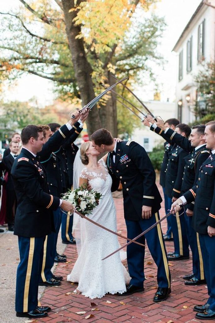Les amis militaires du marié sont en uniforme et brandissent leur sabre pour faire une haie d'honneur 