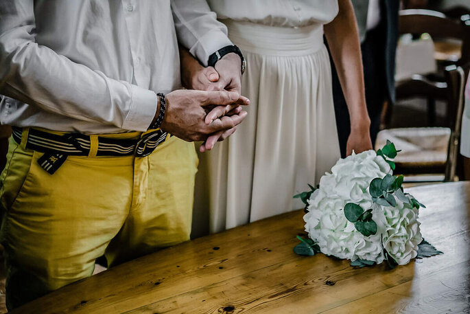 les mariés se tiennent la main lors de la cérémonie le bouquet posé sur la table