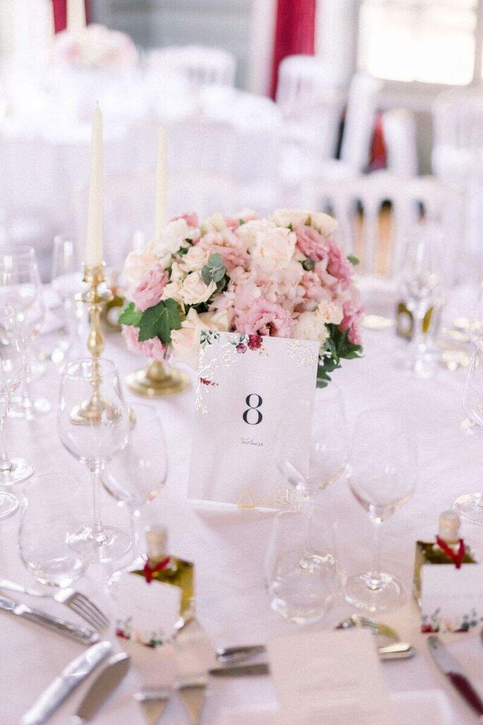 une table de mariage avec pour centres de table des bouquets de fleurs blanches et roses 