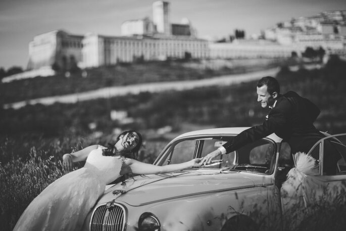Fotomoderna Grillo, ritratto sposi che ridono su cofano auto, bianco e nero