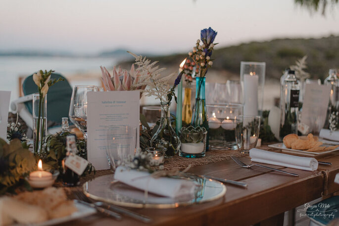 particolare tavola allestita con affaccio sul mare, candele e piatti trasparenti