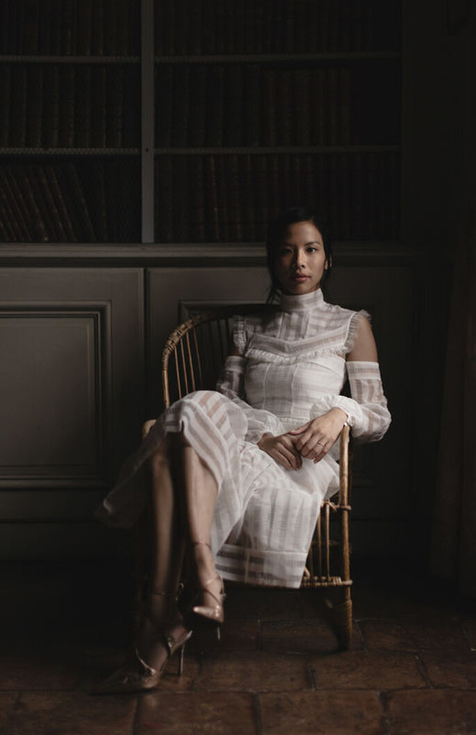 Une mariée assise dans une bibliothèque et photographiée avec un jeu de lumière particulier 