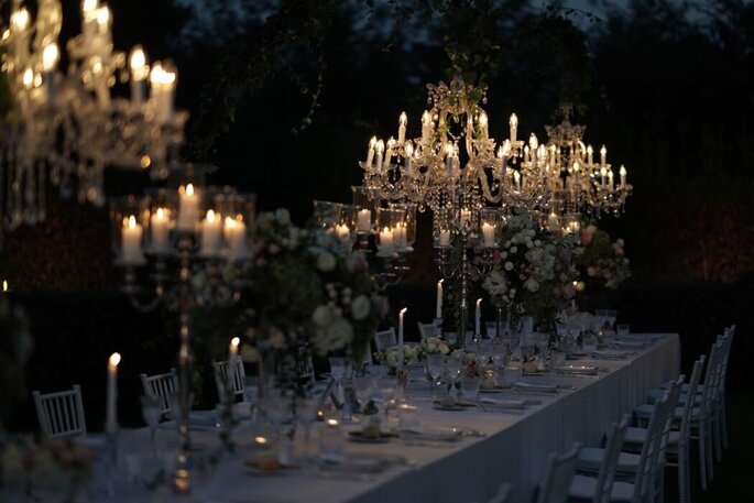 tavola nella penombra, luci di candele, candelabri