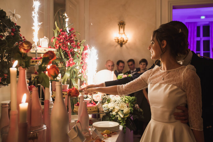 Bougie et ambiance tamisée lors de la découpe d'une pièce montée par un couple de mariés au Château de Santeny 