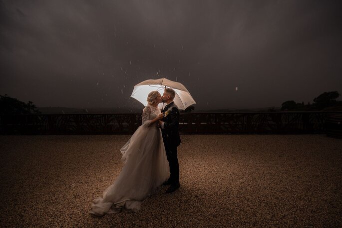 bacio tra sposi sotto la pioggia, notte, ombrello