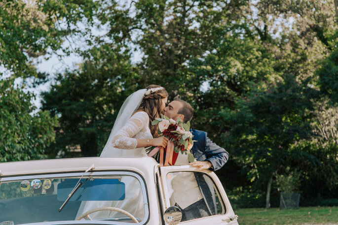 les mariés s'embrassent dans la vieille voiture olrs de leur arrivée