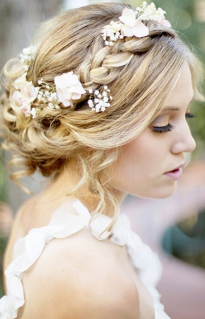 Peinado de novia con corona trenzada y flores. Foto: Trendy Wedding