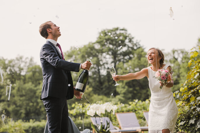 photo des mariés qui rient en ouvrant le Champagne