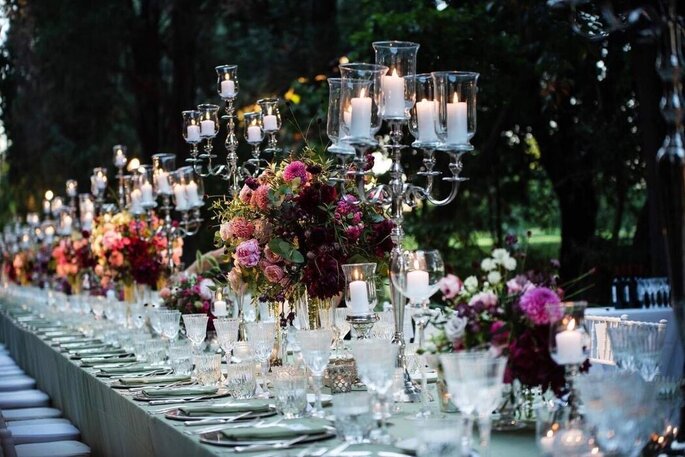 tavolata con tovaglia bianca, fiori colorati e candelabri